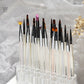 UNS 26-hole acrylic nail brush holder for nail art, displaying multiple brushes organized in a clear acrylic stand.