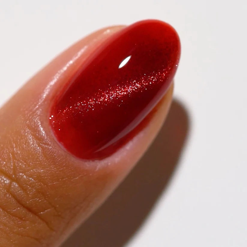 DND DC Gel Cat Eye polish in Wine N' Lust #06, showcasing deep wine red color with cat eye effect on a nail.