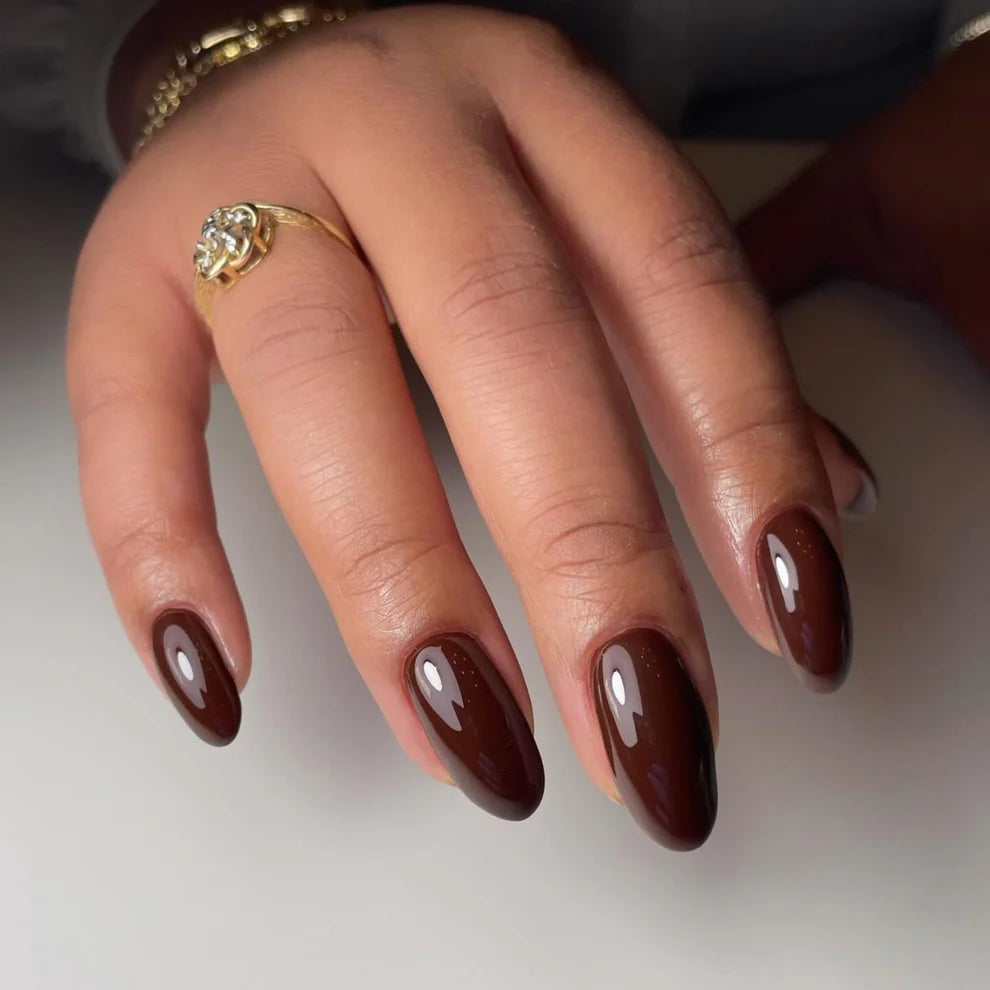 Swatch of DND DC Gel Duo Walnut Brown #052 gel nail polish and lacquer on a nail tip. Rich, warm brown shade with glossy finish.