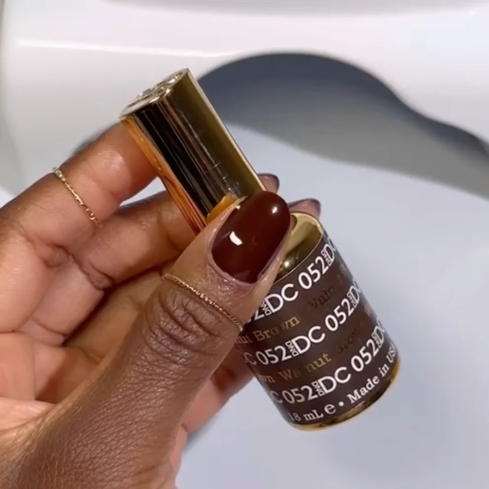 Swatch of DND DC Gel Duo Walnut Brown #052 gel nail polish and lacquer showing glossy finish and rich brown color.