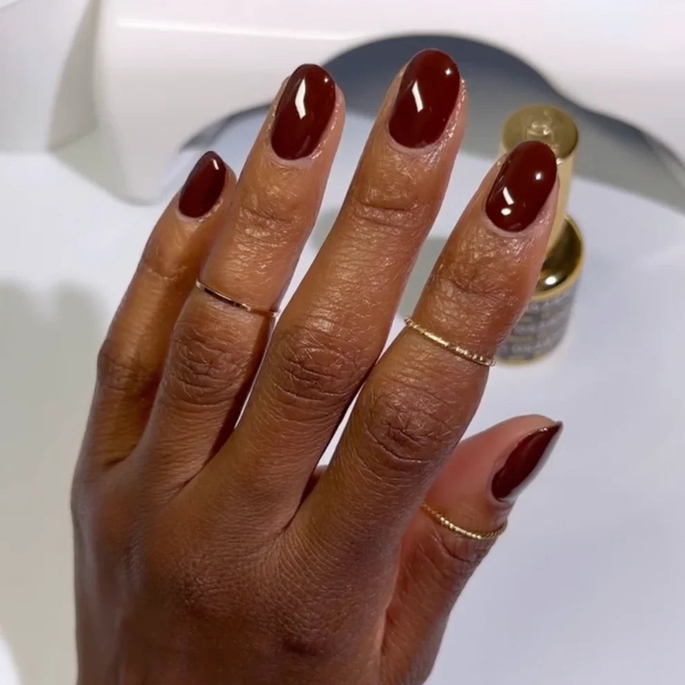 Swatch of DND DC Gel Duo Walnut Brown #052 gel nail polish and lacquer on a nail tip, showcasing rich, glossy brown color.