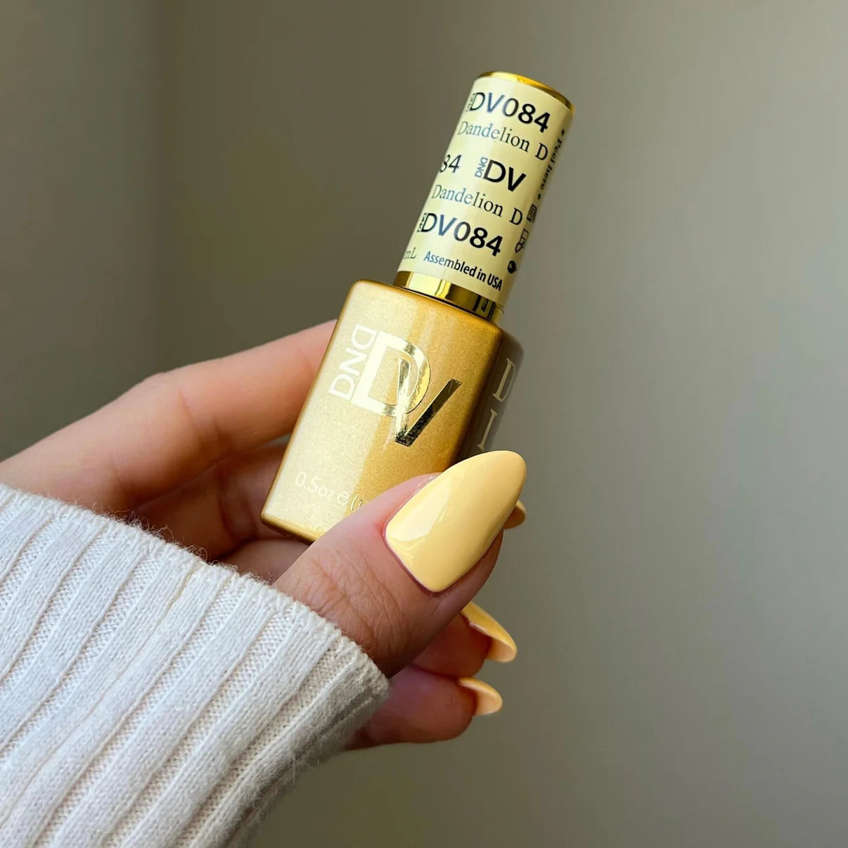 Swatch of DND Diva Duo Gel & Polish in Dandelion 084 showing bright yellow gel nail polish and lacquer finish.