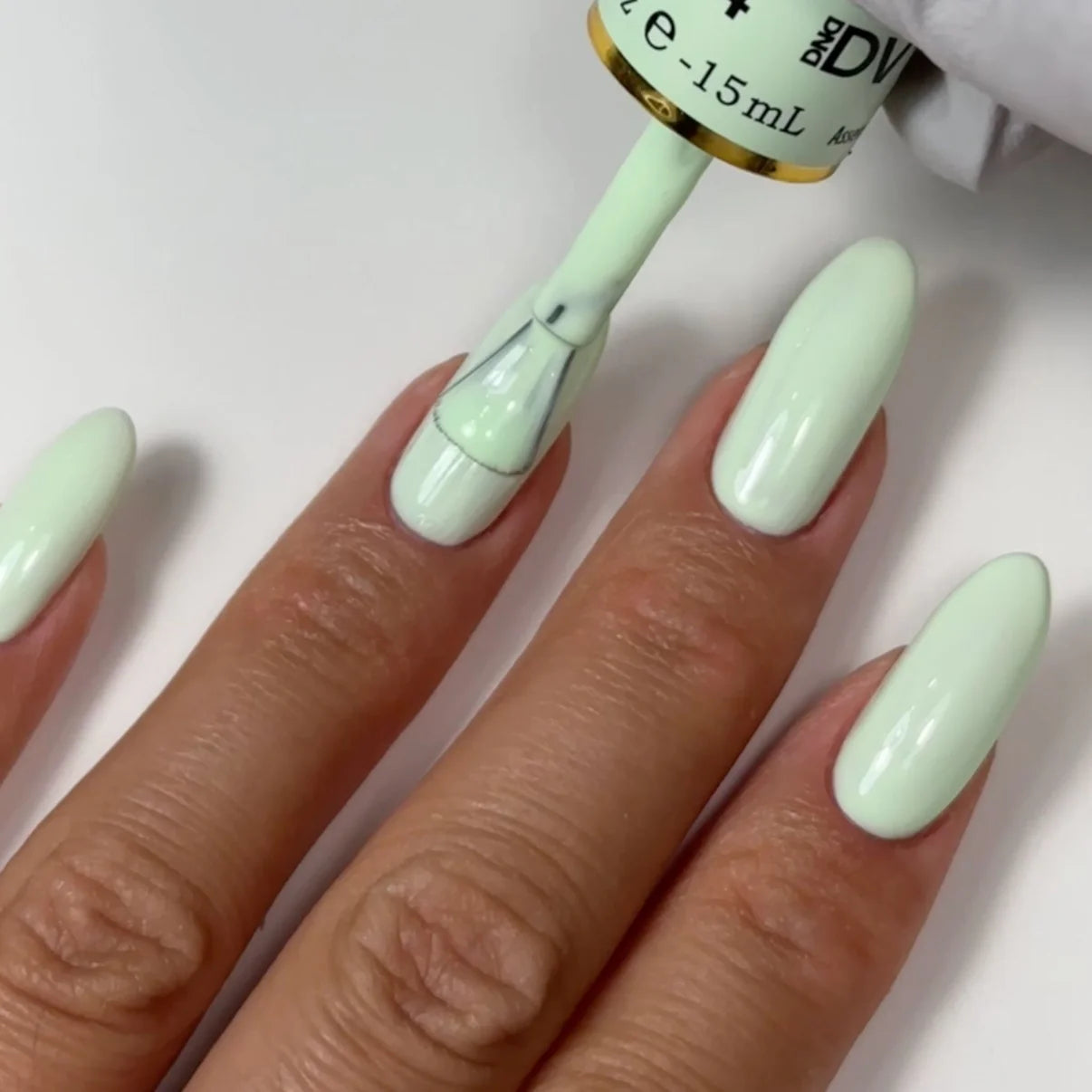 Swatch of DND Diva Duo Gel & Polish in Peppermint Marshmallow 104, showing a creamy mint green gel nail polish and lacquer.