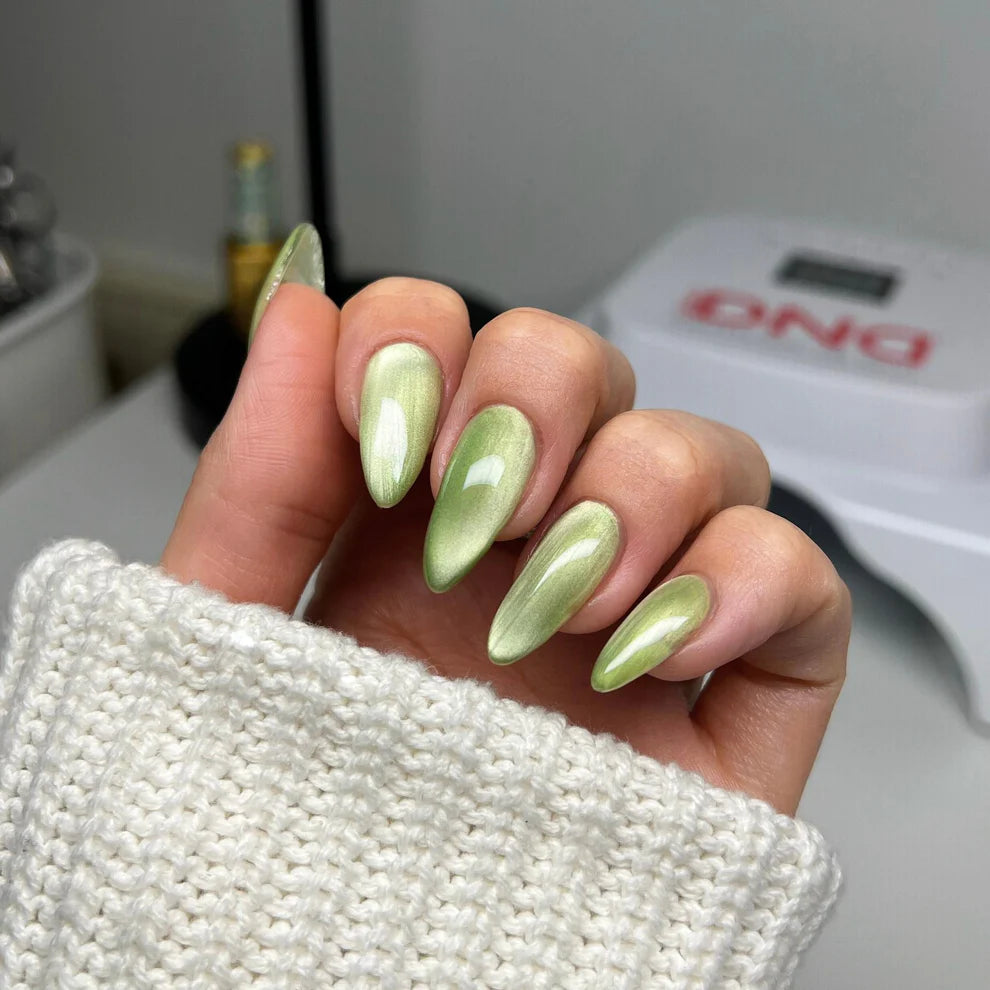 DND Diva 9D Cat Eye Gel Polish in Leafy Prowl, featuring a shimmering green and gold glassball finish on a nail tip.