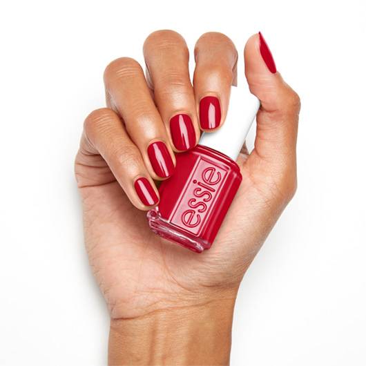 Essie nail lacquer in the shade Not Red-y for Bed, showcasing the vibrant red color on a hand with neatly painted nails.