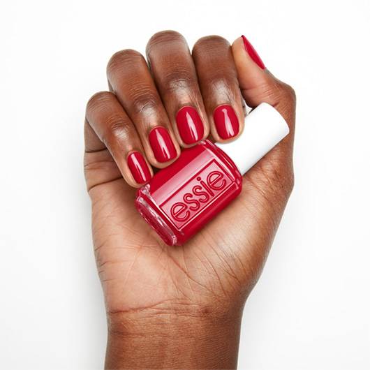 Essie nail lacquer in Not Red-y for Bed #490, showing a close-up of the deep red nail polish on fingers.