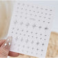 Silver 3D mixed shape nail art decoration stickers by UNS, featuring five pieces of intricate nail embellishments on a white background.