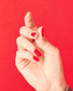 OPI Nail Polish in Cajun Shrimp shade, vibrant coral-orange color, with a glossy finish on a nail display.